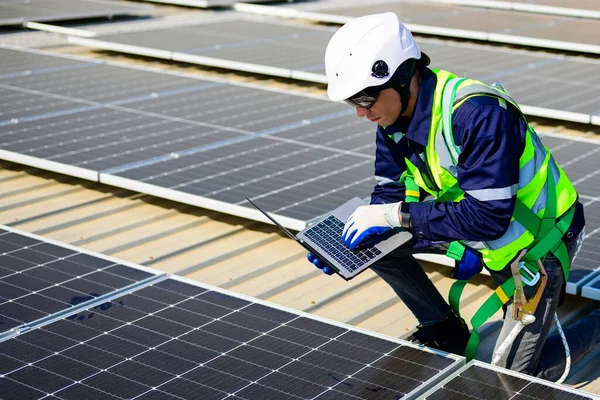Engineer technician using laptop checking and operating system on rooftop of solar cell farm power plant, Renewable energy source for electricity and power, Solar cell maintenance concept