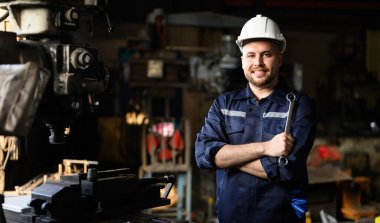Portrait of happy mechanical engineer smiling with arm crossed repairing machine at factory