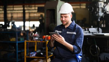 Professional male technician engineer using tablet checking and controlling machine at manufacturing factory