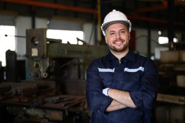 Portrait of engineer worker with white helmet smiling to camera working at manufacturing area