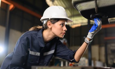 Confident female technician engineer worker checking and inspecting machine at manufacturing factory, Machinery maintenance concept