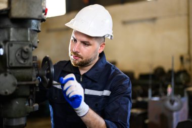 Professional male technician checking and repairing machinery at manufacturing factory