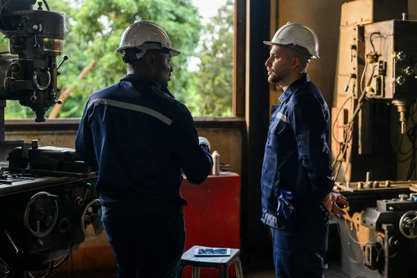 两个穿着安全制服的工业工程师团队在制造厂一起工作 — 图库照片