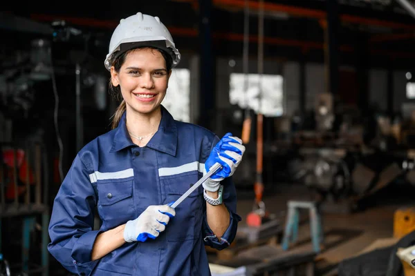 Portrait of happy female industrial worker in white hard hat smiling to camera working at manufacturing plant, Industrial engineer portrait