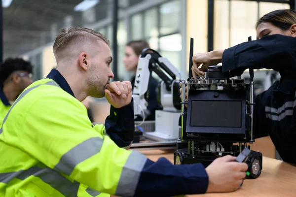 Group of maintenance engineers checking and repairing automatic robotic machine at industrial factory, Technicians workers working with robotic system in factory, Technology and innovation concept