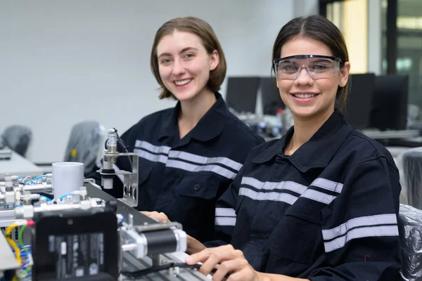 在工厂使用手提电脑和操作自动化机器人的快乐的女工程师团队 在工厂使用机器人系统的技术人员 — 图库照片