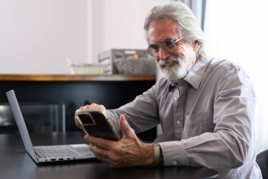 Senior grandfather using laptop and smart phone at home, Happy retirement people relaxing and resting at home, Healthy and happy senior people concept