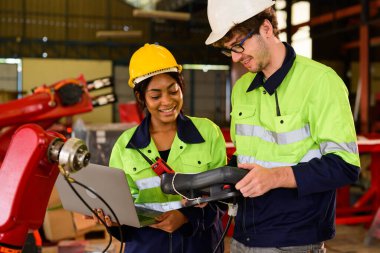 Technician engineer holding robot controller checking and repairing automatic robotic machine at industrial factory, Worker working with robotic arm system in factory