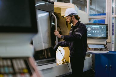 Professional technician checking and repairing part of automatic machine at industrial factory