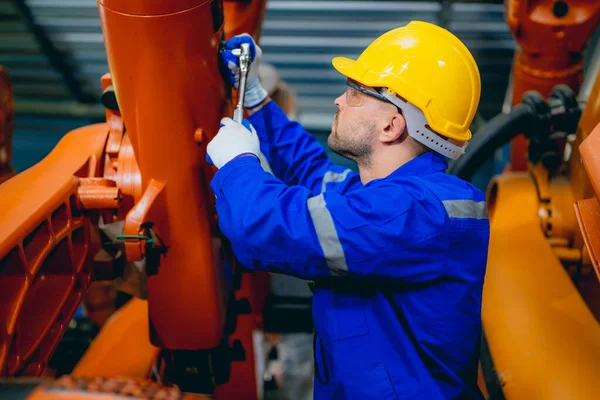Professional maintenance worker working with machine robotic arms at industrial factory, Technician engineer checking safety of machine and maintenance robotic arms
