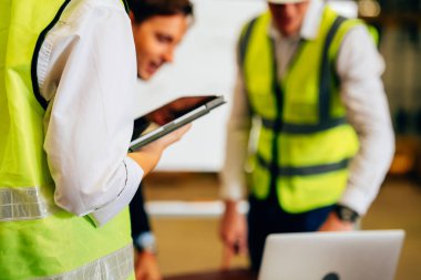Happy warehouse engineer with safety vest using tablet for checking goods and supplies on shelves with goods background in warehouse store, Logistic and business export concept