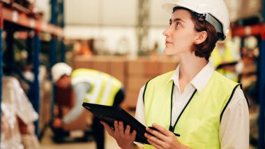 Happy warehouse engineer with safety vest using tablet for checking goods and supplies on shelves with goods background in warehouse store, Logistic and business export concept