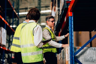 Group of warehouse workers with safety vest talking and discussing plan together, Workers checking and controlling goods working in store factory, Warehouse worker with teamwork concept