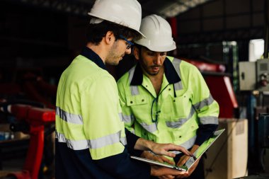 Endüstriyel fabrikada otomatik robotik makineyi kontrol eden teknisyen mühendisi fabrikadaki üretim hattı makine sisteminde çalışan işçi