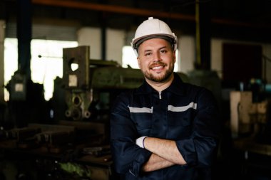 Portrait of engineer worker with white helmet smiling to camera working at manufacturing area