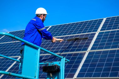 Worker cleaning solar panel at solar cell farm, People working with alternative energy