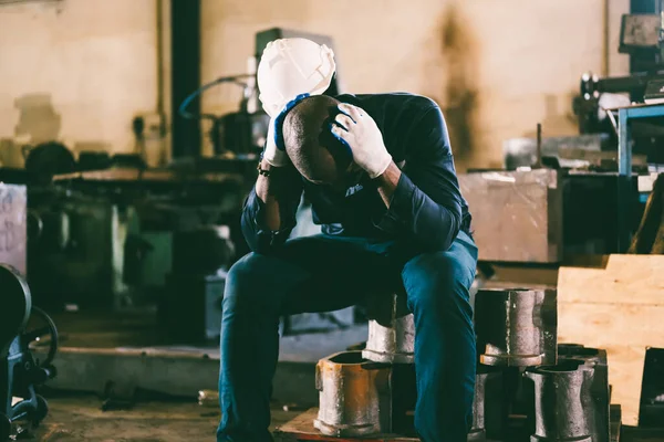 Unhappy and tired male industrial worker with headache working in hardworking position