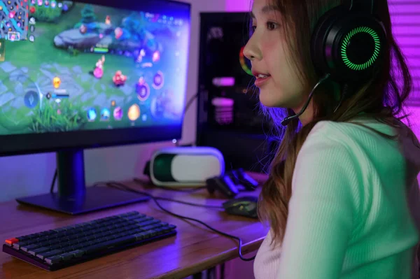 Young female game streamer playing online game on computer at home, Gamer woman wearing headsets taking on microphone with teammates, Gamer lifestyle, E-Sport online gaming technology