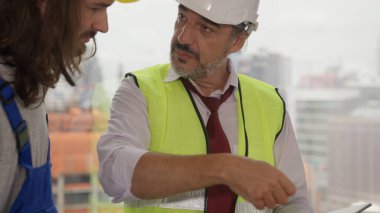 Professional construction engineer foreman discussing and brainstorming with architects workers on new building at construction site, Engineer with architecture and building construction concept