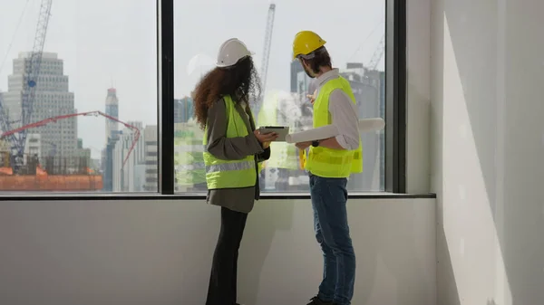 Couple of professional architects workers using tablet brainstorming and planing new modern office at building site, Two construction workers working together while visiting new building