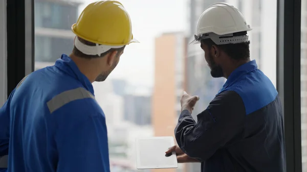 Professional male contractor with safety helmet talking and brainstorming with electrician technician engineer at workplace, Technician engineer foreman discussing with team at building site