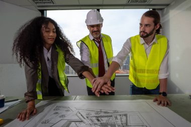 Group of construction engineers touching and stacking hands supporting together at construction building, Happy construction workers team working with happiness, Teamwork concept