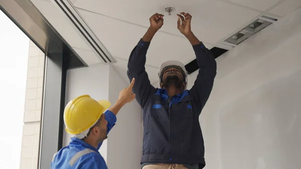Engineers team installing fire sprinkler in office at building site, Technicians workers checking fire alarm systems and automatic sprinkler systems at new building construction site