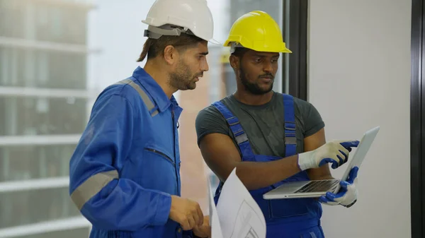 Contractor worker and professional architect holding laptop talking and consulting project plan together working on construction site, Building in construction process interior concept