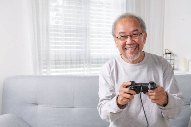 Senior using joystick, Senior holding joystick to play game, Elderly smiling, Elderly laughing on sofa using controller play game, Senior smart life with gaming