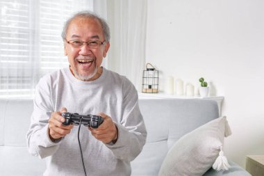 Senior using joystick, Senior holding joystick to play game, Elderly smiling, Elderly laughing on sofa using controller play game, Senior smart life with gaming