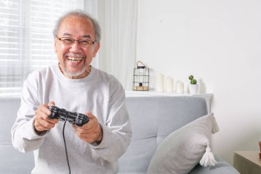 Senior using joystick, Senior holding joystick to play game, Elderly smiling, Elderly laughing on sofa using controller play game, Senior smart life with gaming