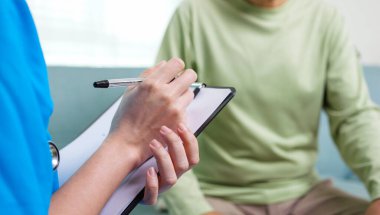 Young doctor examining senior patient at home visit, Senior man consulting medicine with pharmacist, Caregiver nurse taking care of elderly grandfather sitting on sofa at home, Medical service concept