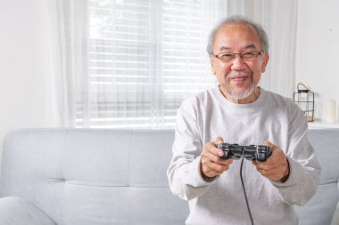 Senior using joystick, Senior holding joystick to play game, Elderly smiling, Elderly laughing on sofa using controller play game, Senior smart life with gaming