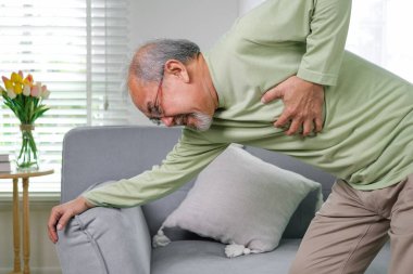 Heart attack symptoms, Senior heart attack suffering indoor, Elderly hand touching heart, Emergency of senior has heart attack suddenly, Face of suffering from unhealthy, Healthcare medical