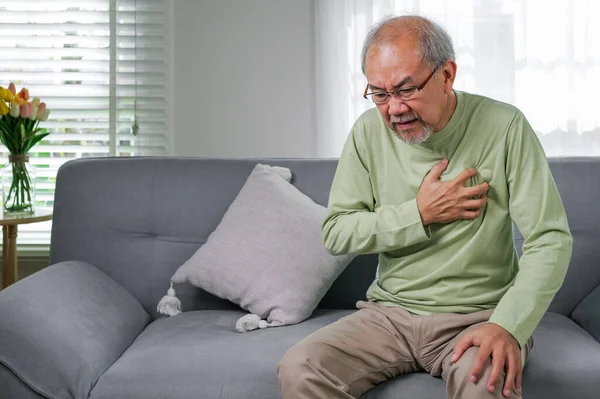 Heart attack symptoms, Senior heart attack suffering indoor, Elderly hand touching heart, Emergency of senior has heart attack suddenly, Face of suffering from unhealthy, Healthcare medical
