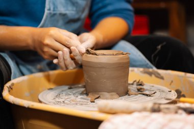 Close up on skillful hands making and sculpting pottery jar on potter wheel with tools and water in workshop, Creative and artwork, Handmade craft