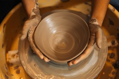 Close up on skillful hands making and sculpting pottery jar on potter wheel with tools and water in workshop, Creative and artwork, Handmade craft