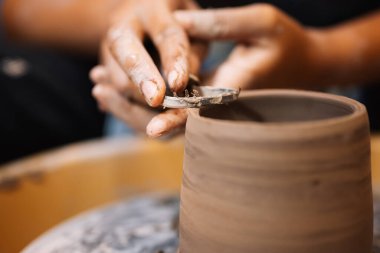 Close up on skillful hands making and sculpting pottery jar on potter wheel with tools and water in workshop, Creative and artwork, Handmade craft