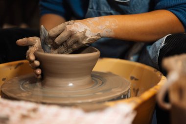 Becerikli ellerle çömlek kavanozunu çömlekçi çarkında yapmak ve yontmak üzerine atölyede aletler ve su, yaratıcı ve sanat eserleri, el yapımı el işi.