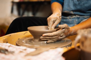 Close up on skillful hands making and sculpting pottery jar on potter wheel with tools and water in workshop, Creative and artwork, Handmade craft