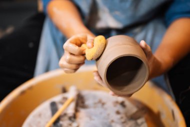 Close up on skillful hands making and sculpting pottery jar on potter wheel with tools and water in workshop, Creative and artwork, Handmade craft