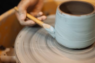 Close up on skillful hands making and sculpting pottery jar on potter wheel with tools and water in workshop, Creative and artwork, Handmade craft