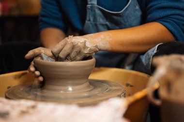 Close up on skillful hands making and sculpting pottery jar on potter wheel with tools and water in workshop, Creative and artwork, Handmade craft