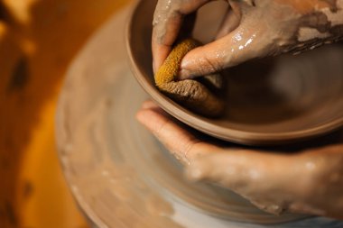 Close up on skillful hands making and sculpting pottery jar on potter wheel with tools and water in workshop, Creative and artwork, Handmade craft