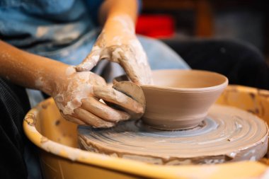 Close up on skillful hands making and sculpting pottery jar on potter wheel with tools and water in workshop, Creative and artwork, Handmade craft