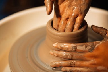 Close up on skillful hands making and sculpting pottery jar on potter wheel with tools and water in workshop, Creative and artwork, Handmade craft