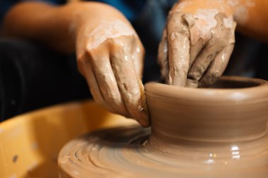 Becerikli ellerle çömlek kavanozunu çömlekçi çarkında yapmak ve yontmak üzerine atölyede aletler ve su, yaratıcı ve sanat eserleri, el yapımı el işi.