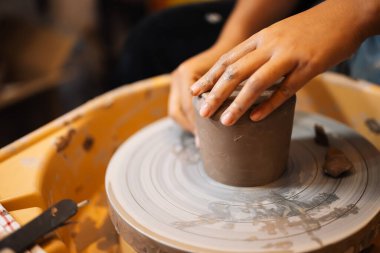 Close up on skillful hands making and sculpting pottery jar on potter wheel with tools and water in workshop, Creative and artwork, Handmade craft
