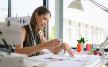Happy female dressmaker working in workshop, Female tailor fashion designer checking measurements and fitting of dress, Tailoring clothing on mannequin garment workshop studio, Small business owner