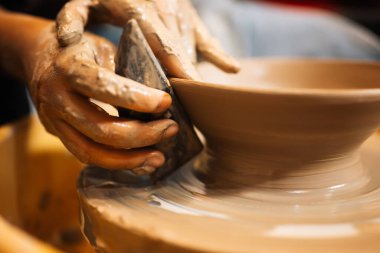 Close up on skillful hands making and sculpting pottery jar on potter wheel with tools and water in workshop, Creative and artwork, Handmade craft